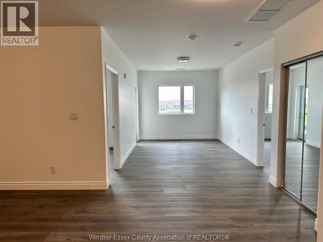 A spacious room with wooden floors and a large window.