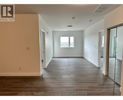 A spacious room with wooden floors and a large window.
