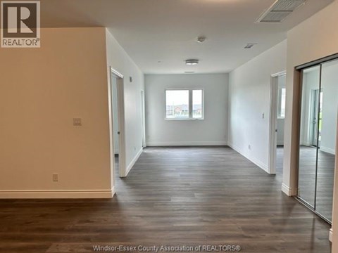A spacious room with wooden floors and a large window.