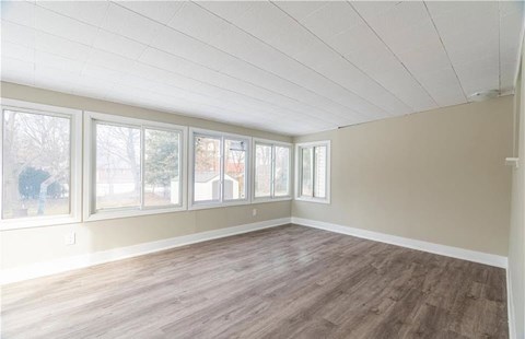 Empty room with white ceiling and wooden floor.