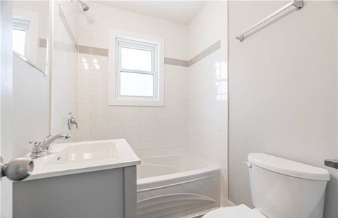 A white bathroom with a tub, sink, and toilet.