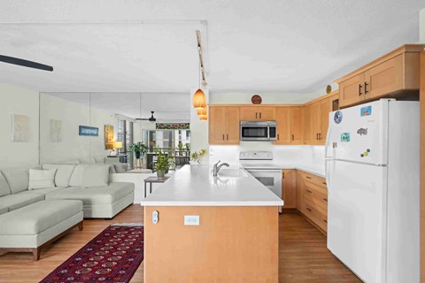 A kitchen with a white refrigerator and a white sofa.