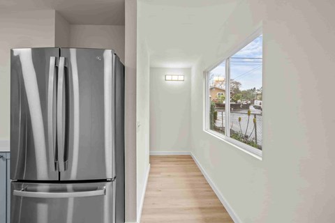 A modern kitchen with a stainless steel refrigerator and wooden flooring.