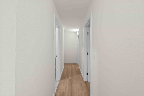 A long hallway with white walls and wood floors.