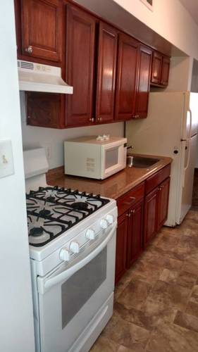 A kitchen with a white stove top oven and brown cabinets.