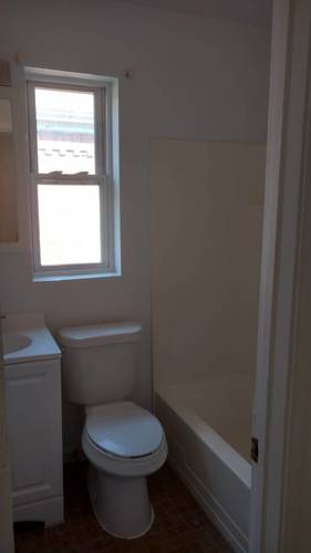 A white toilet sits next to a window in a bathroom.