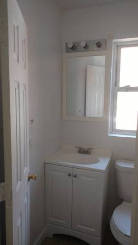 A white bathroom with a toilet, sink and medicine cabinet.