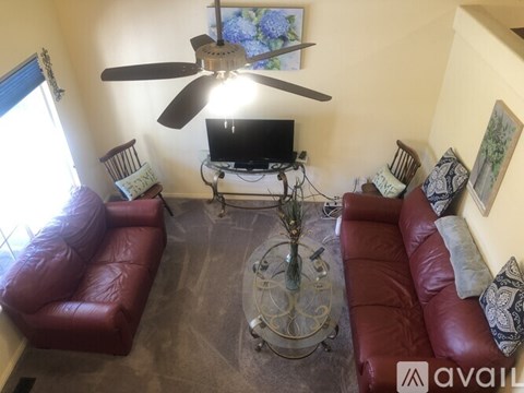 A living room with red leather couches and a television on a stand.