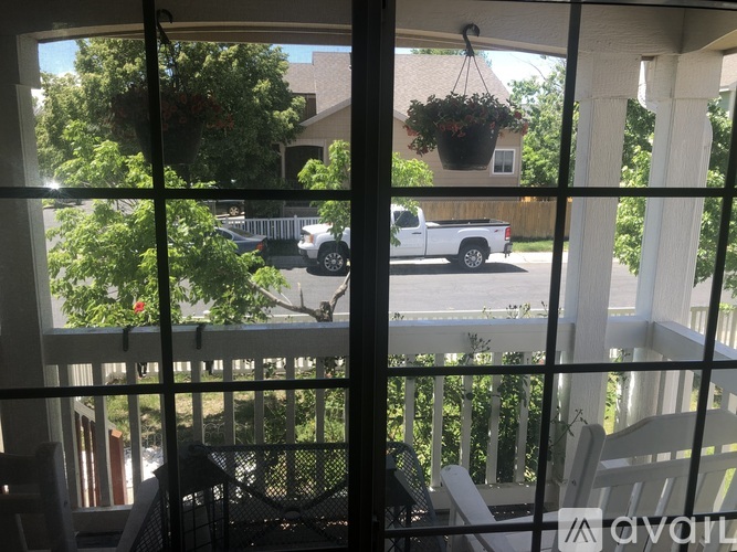 A view from a balcony looking out at a white truck and a house.