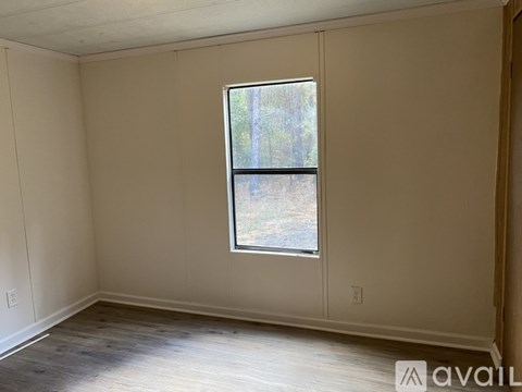 A room with a window and wooden flooring is available for rent.