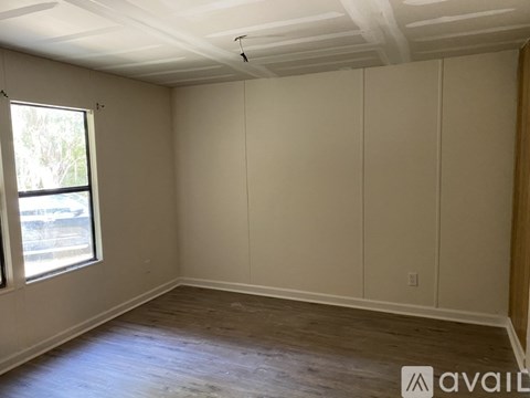 A room with a window and wooden flooring is available for rent.