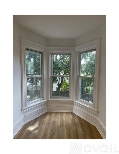 A room with a wooden floor and three windows.