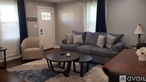 A living room with a grey couch, a brown coffee table, and a beige armchair.