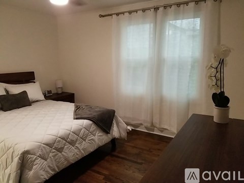 A bedroom with a bed, nightstand, and window with curtains.