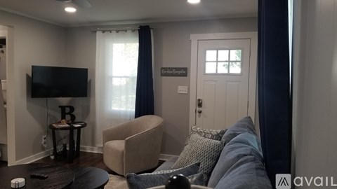 A living room with a grey couch and a flat screen TV mounted on the wall.
