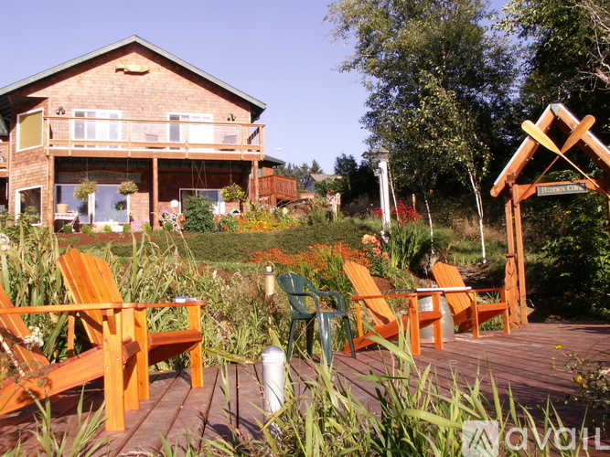 A wooden deck with orange chairs and a pergola.