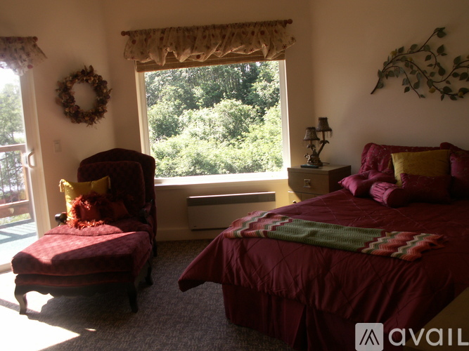 A bedroom with a bed, chair, and window.