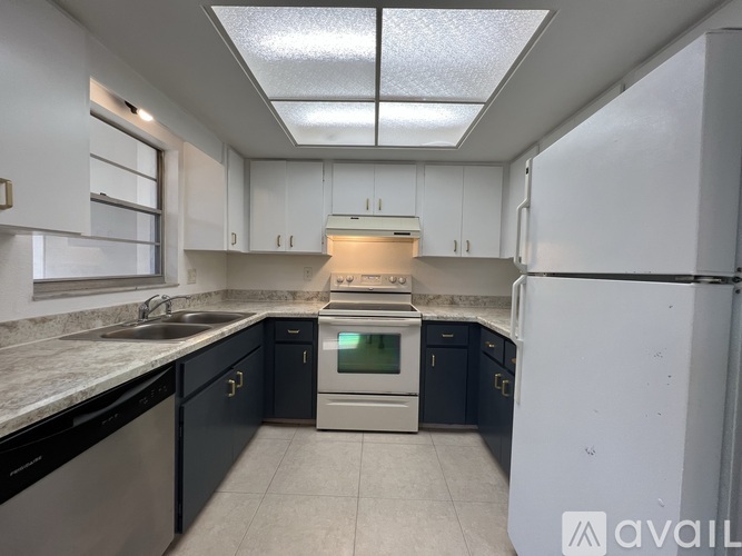 A kitchen with black cabinets and a white fridge.