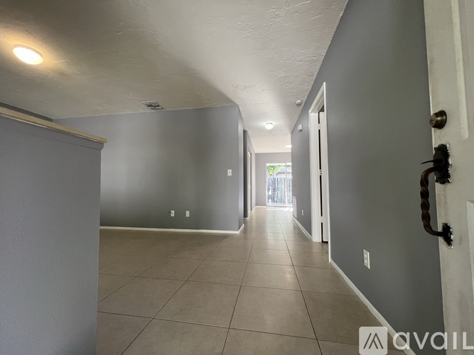 A long hallway with a door on the right and a window in the distance.
