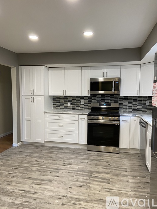 A kitchen with white cabinets and a black and white checkered backsplash.