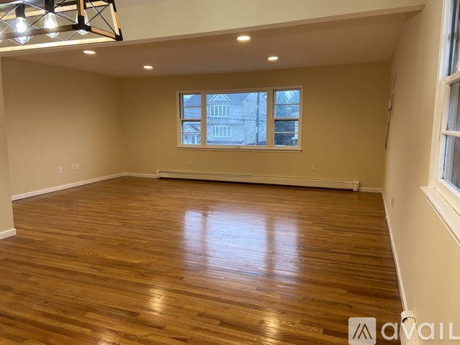 A spacious room with wooden flooring and a large window.