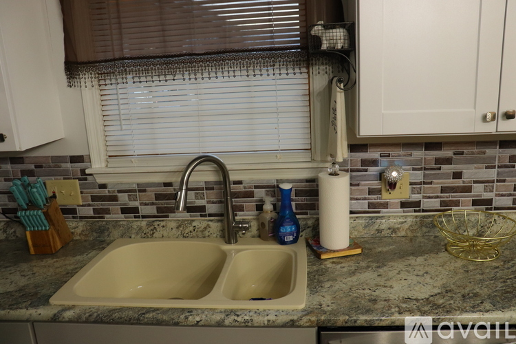 A kitchen sink with a granite counter top and a window above it.