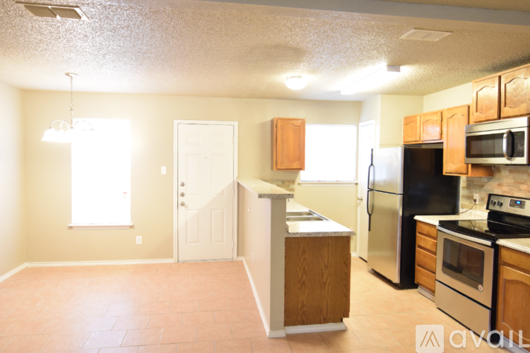 A kitchen with wooden cabinets and a black refrigerator.