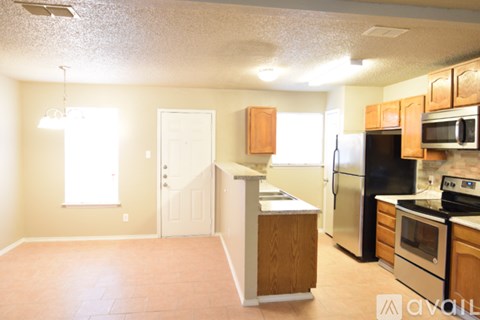A kitchen with wooden cabinets and a black refrigerator.