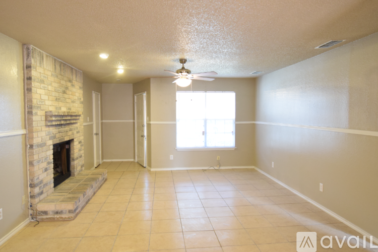 A spacious living room with a stone fireplace and tile flooring.