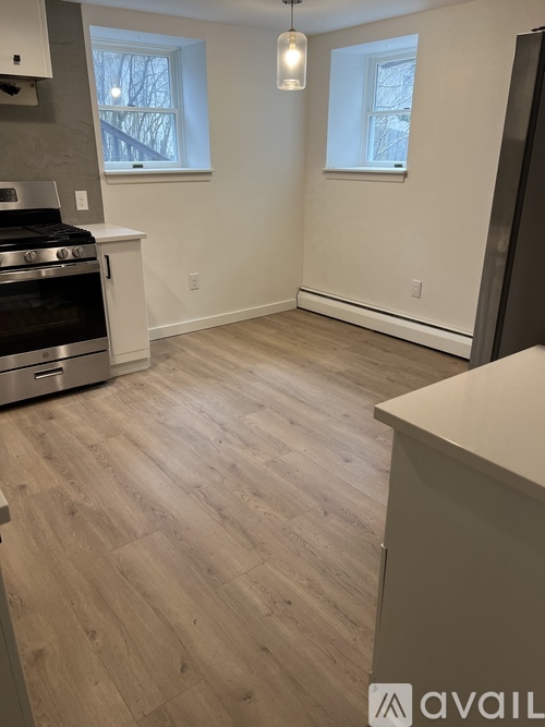 A kitchen with a stove top oven and a wooden floor.