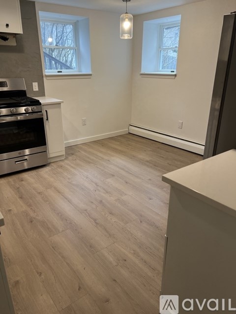 A kitchen with a stove top oven and a wooden floor.