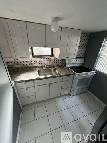 A kitchen with white cabinets and a tiled floor.