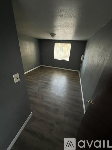 A room with a window and wooden flooring.