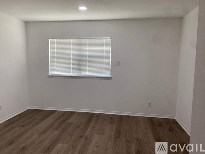 A room with wooden flooring and a window with blinds.