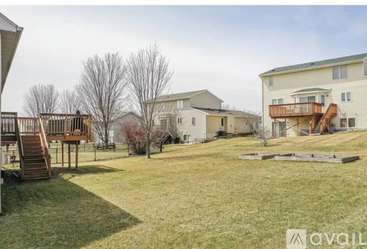 A grassy area with a house and a deck in the background.