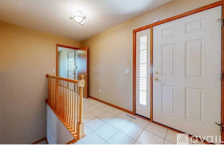 A hallway with a white door and a wooden banister.