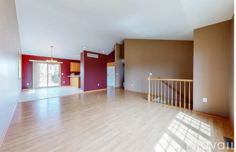 A spacious room with wooden floors and a balcony on the right side.