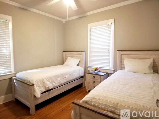 A bedroom with two beds and a nightstand.