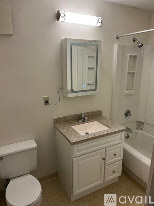 A bathroom with a toilet, sink, mirror, and bathtub.