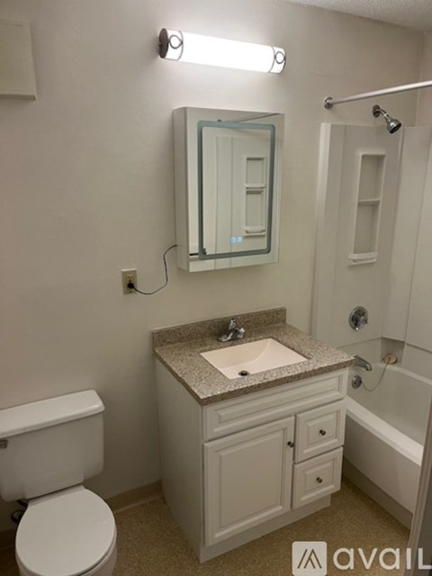 A bathroom with a toilet, sink, mirror, and bathtub.
