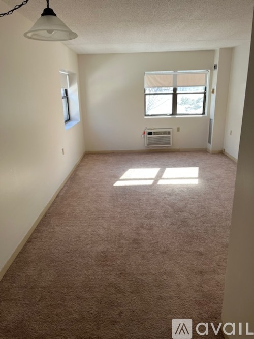 A room with a carpeted floor and a window with blinds.