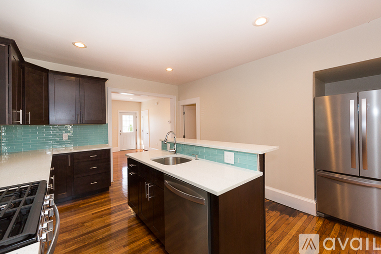 A kitchen with dark wood cabinets and a stainless steel refrigerator.