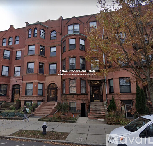 A red brick building with a tree in front of it.