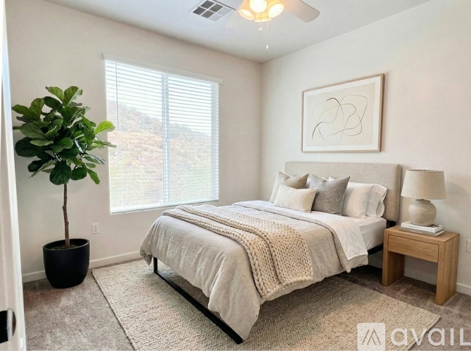 A well-lit bedroom with a large bed and a potted plant.