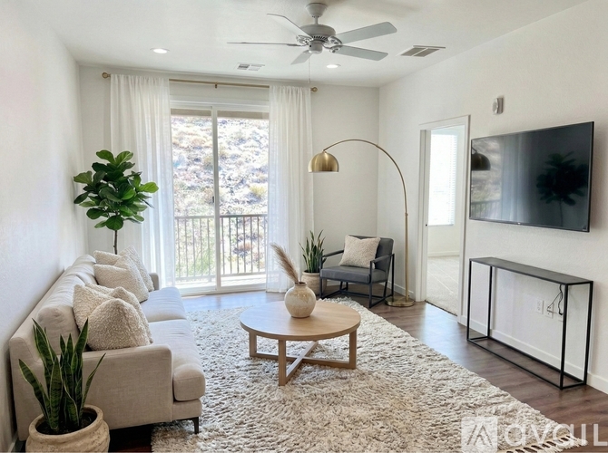A living room with a white couch, a wooden coffee table, and a flat-screen TV mounted on the wall.