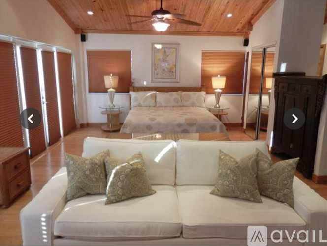A large white couch with four cushions sits in the middle of a spacious room.