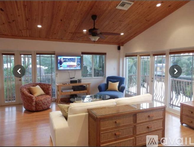 A living room with a white couch and a television on the wall.