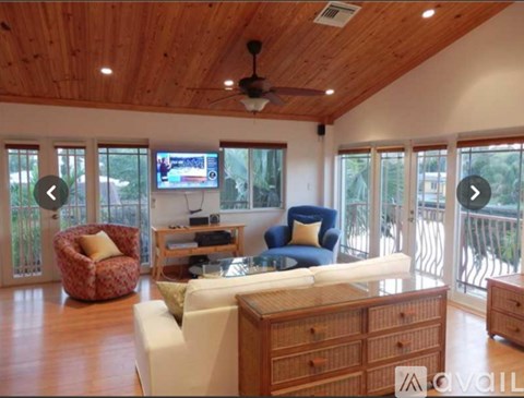 A living room with a white couch and a television on the wall.