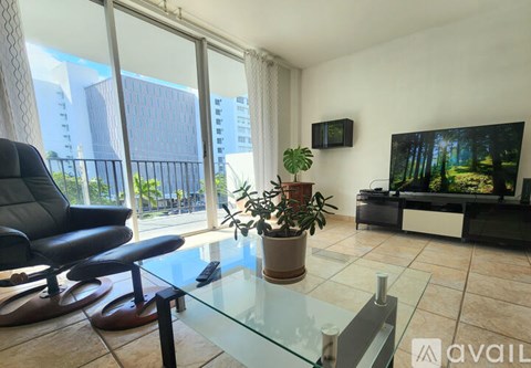 A living room with a glass table and a television on the wall.