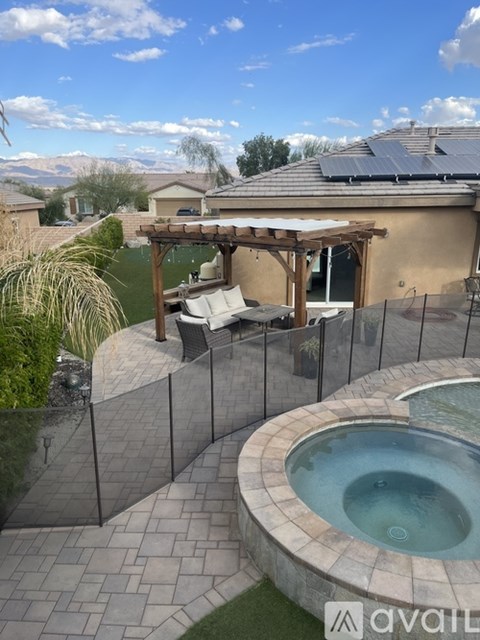 A hot tub is surrounded by a fence and a patio with a table and chairs.
